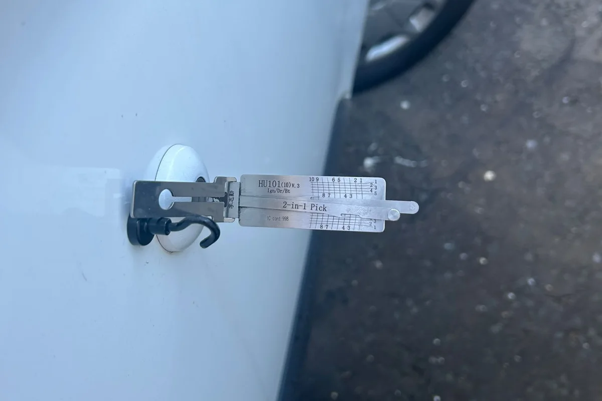 locksmith pick tool in the door lock of a locked white car