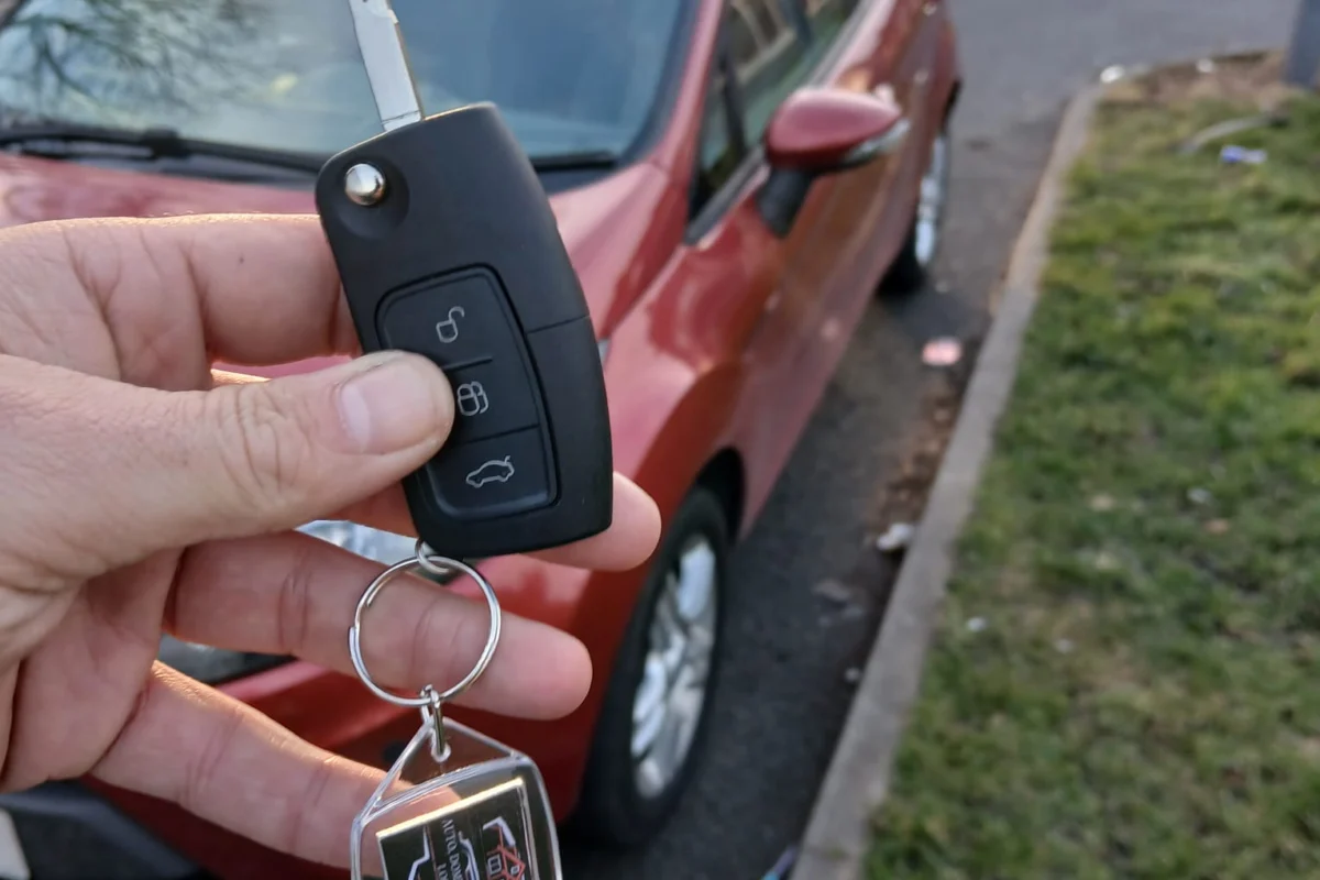 Programmed replacement key beside a red car