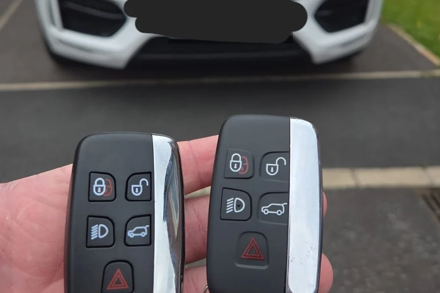 Jaguar smart keys beside a white Jaguar