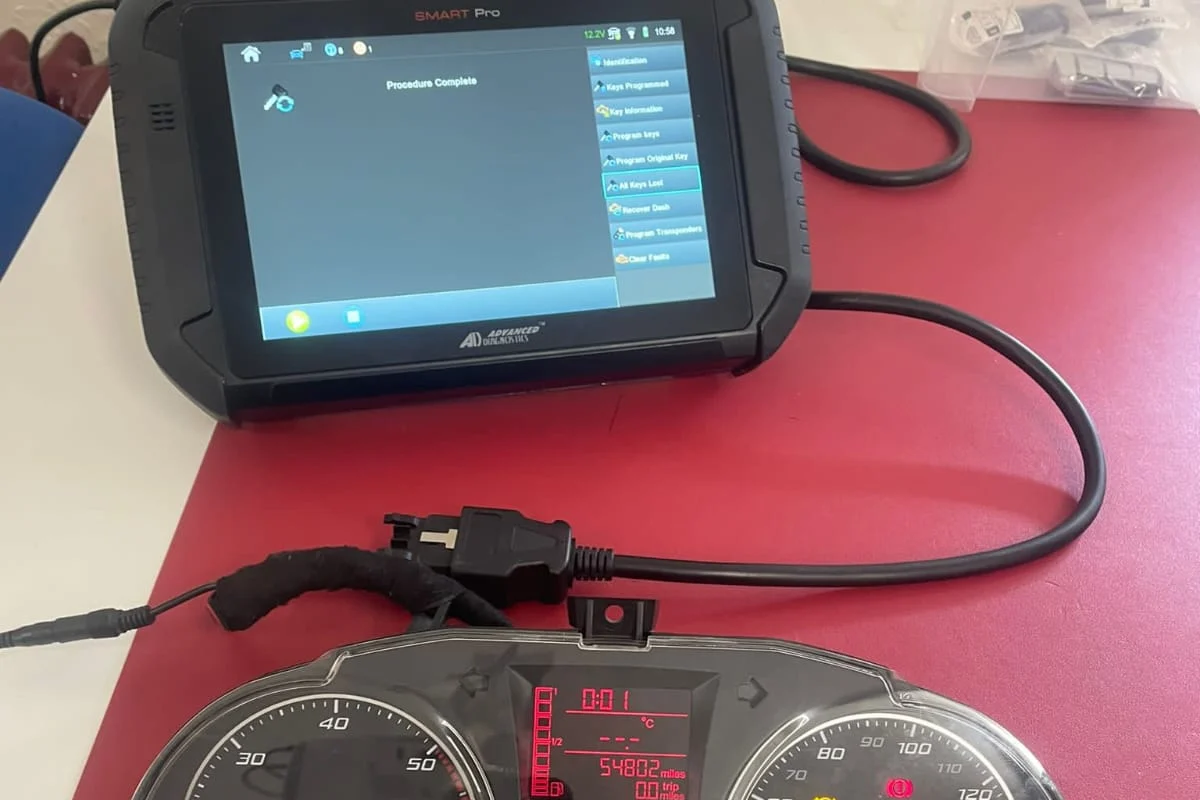 Key programming tool beside a car instrument cluster during car key programming by make