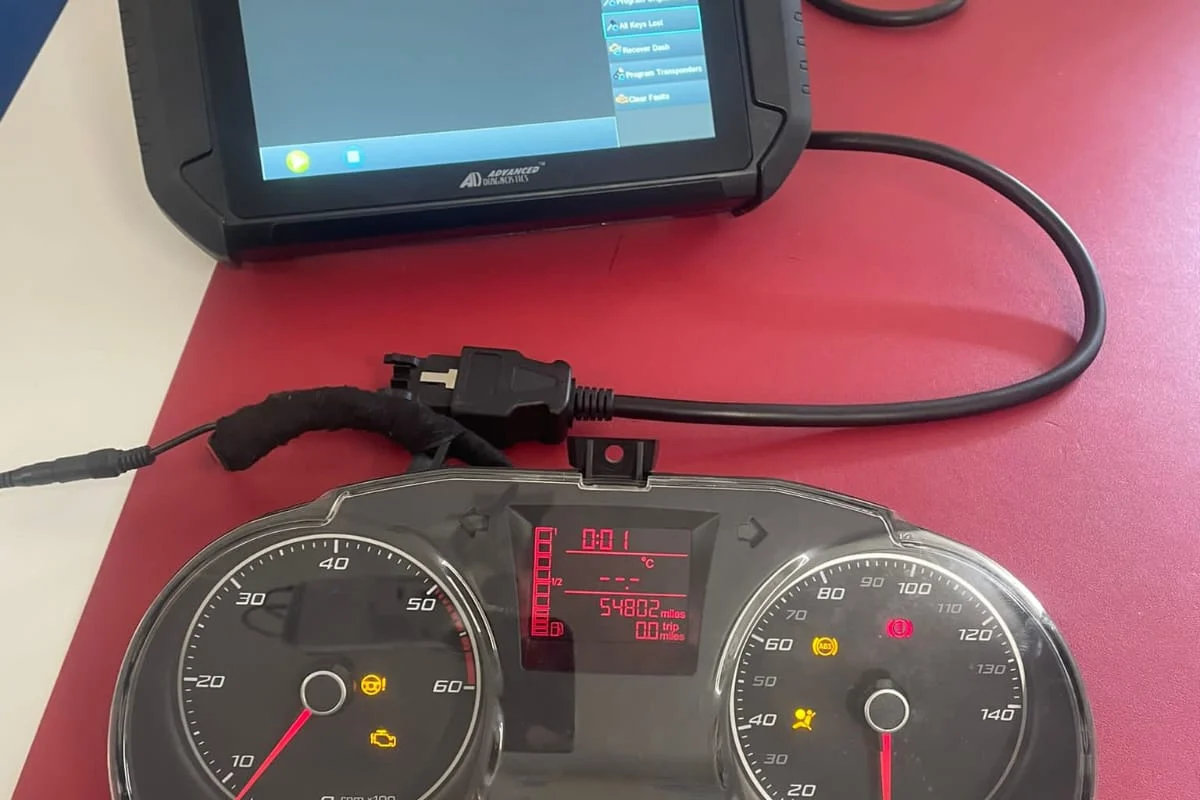 Diagnostic programming tool beside a car instrument cluster