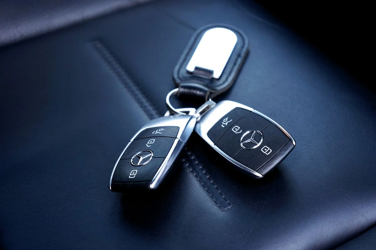 Two Mercedes car keys on a leather seat