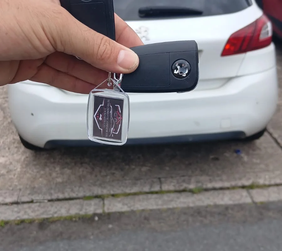 New flip key held beside a white car after programming